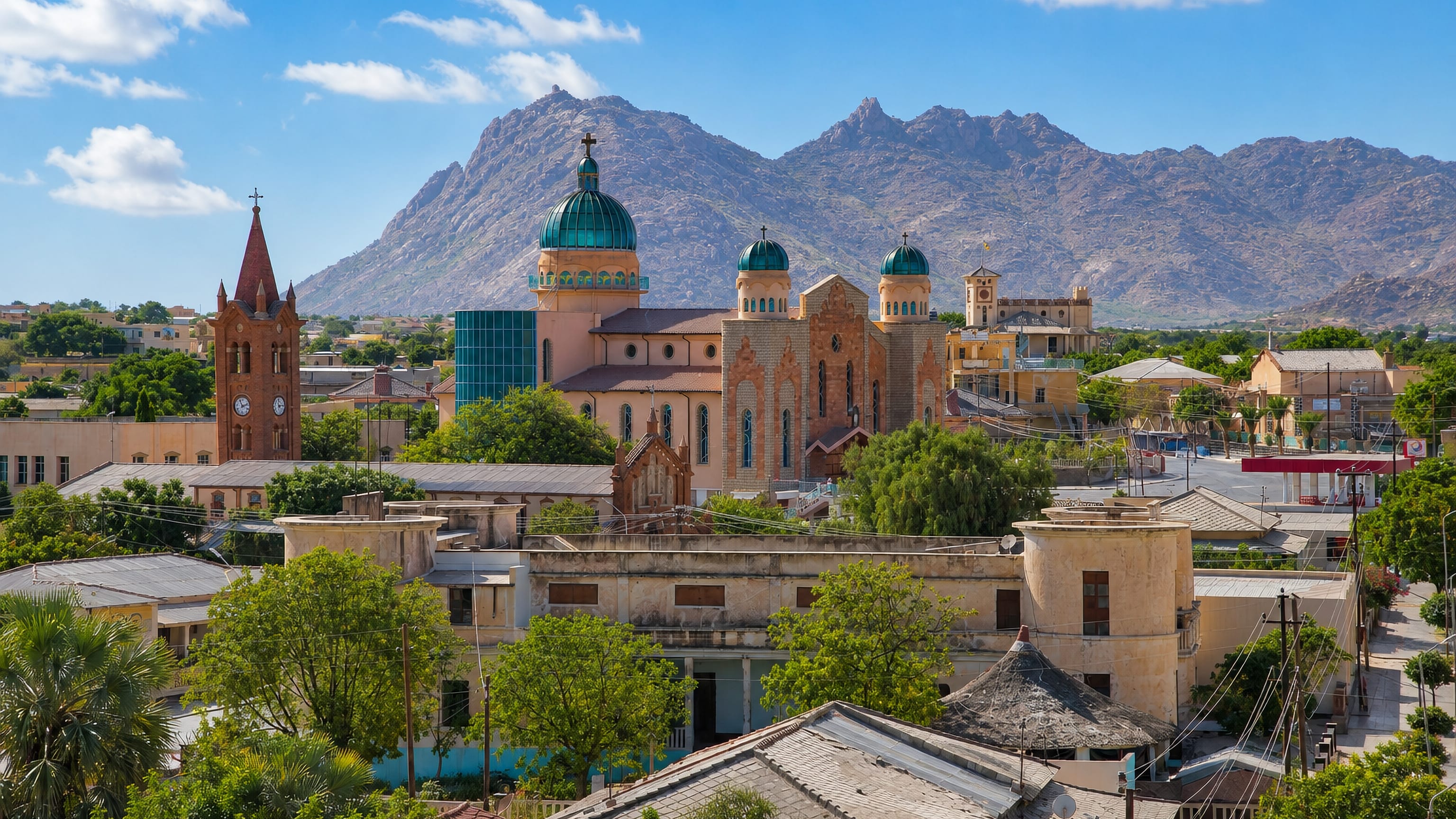 Keren, Eritrea, with a green-domed cathedral and brick campanile below the town's bare granite peaks.