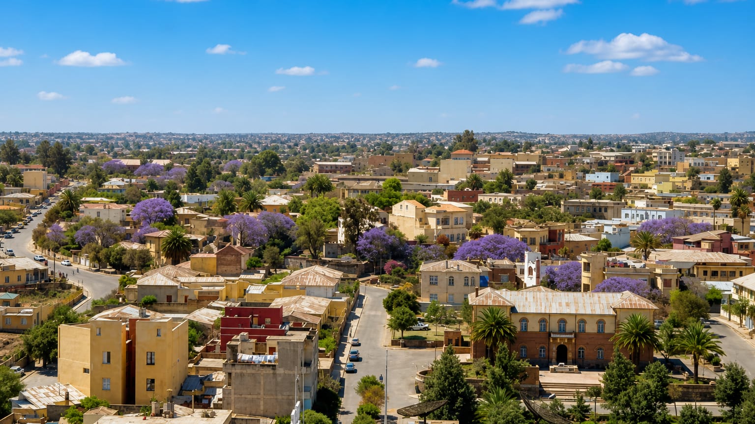 Asmara, Eritrea, low-rise cityscape with blooming jacaranda trees, palms and Italian-era buildings.