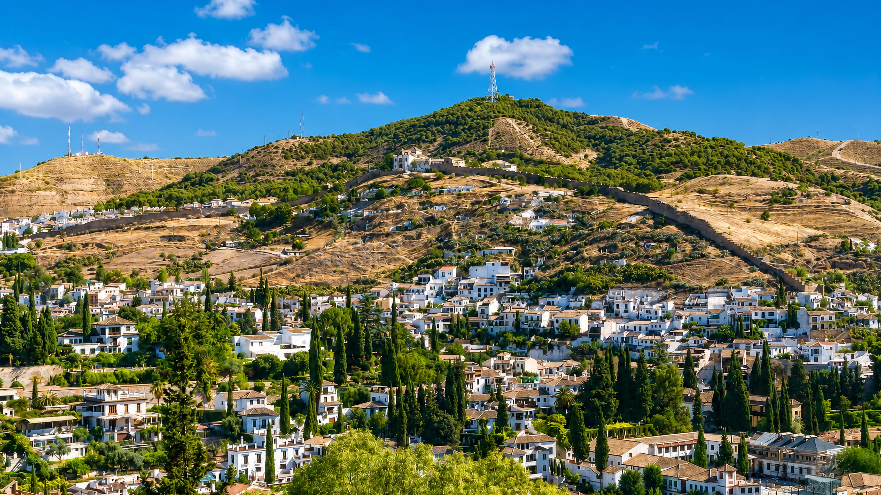 Whitewashed houses and cypresses climbing the hillside below the Albaicín wall and San Miguel Alto above Granada.