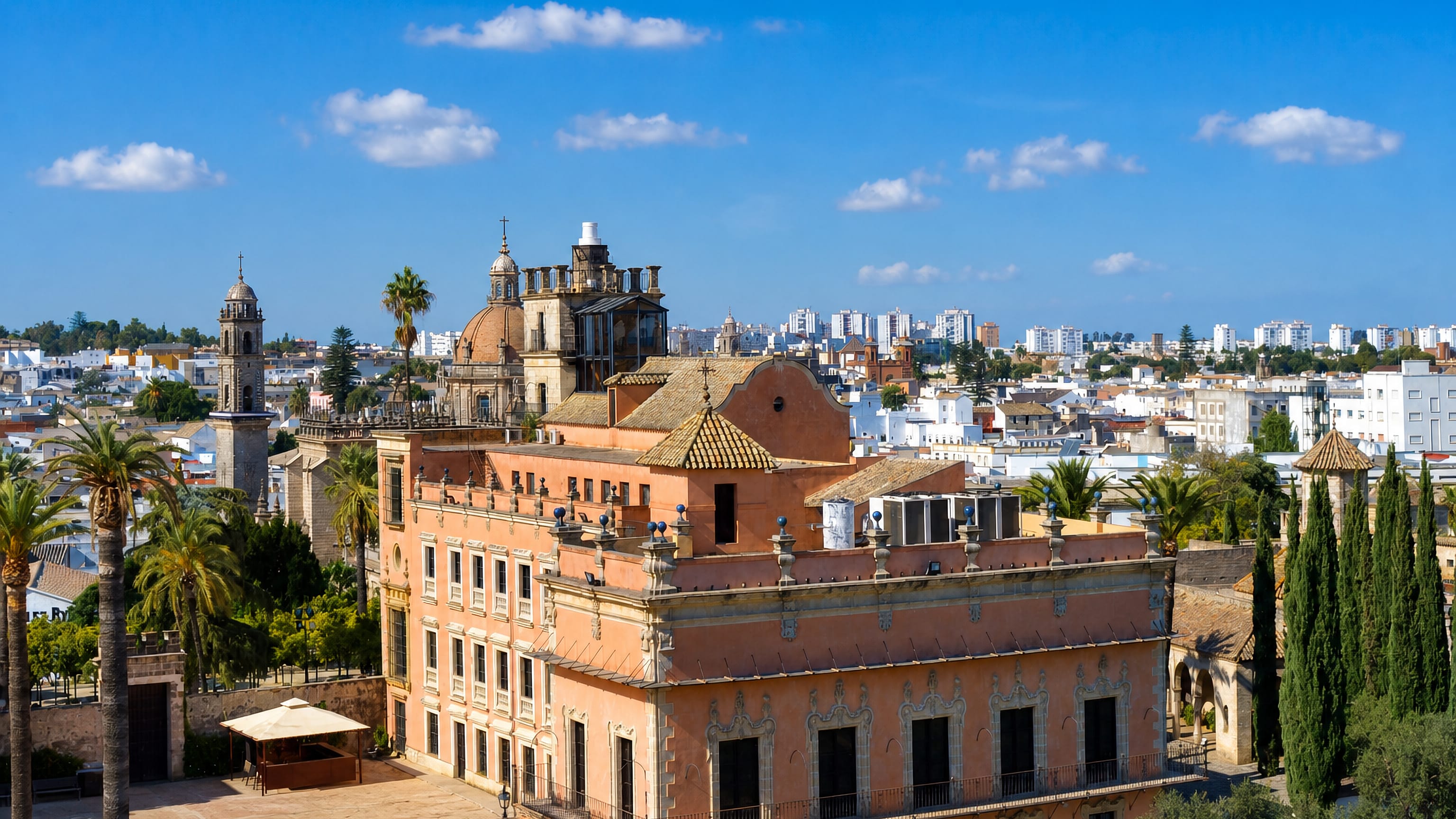 Jerez de la Frontera's pink Palacio de Villavicencio with the cathedral dome and bell tower over whitewashed rooftops.