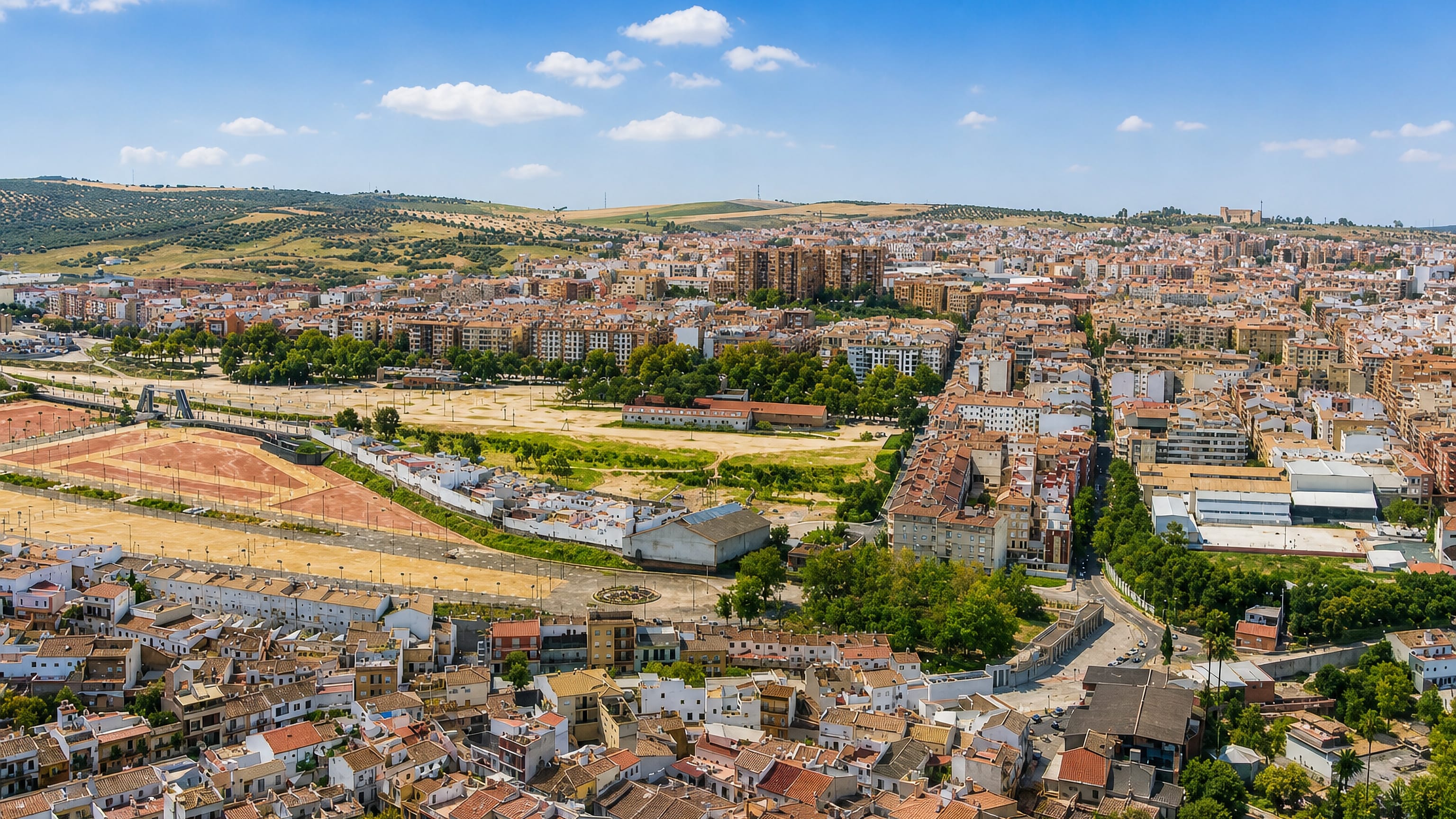 Aerial view over the terracotta rooftops of Linares, Andalusia, with olive-covered hills beyond the town.