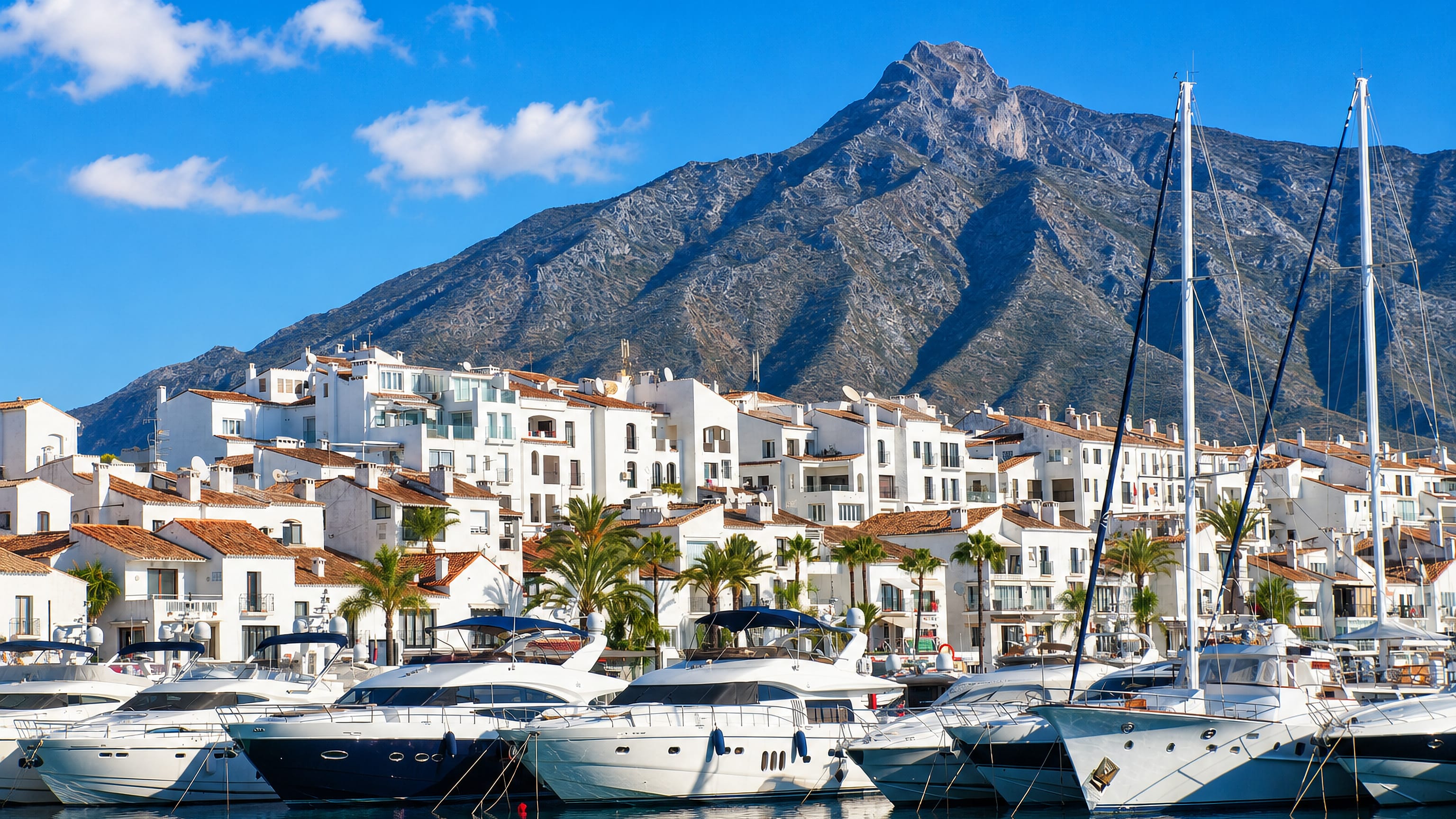 Puerto Banús marina in Marbella, white Andalusian apartments and moored yachts below La Concha mountain.
