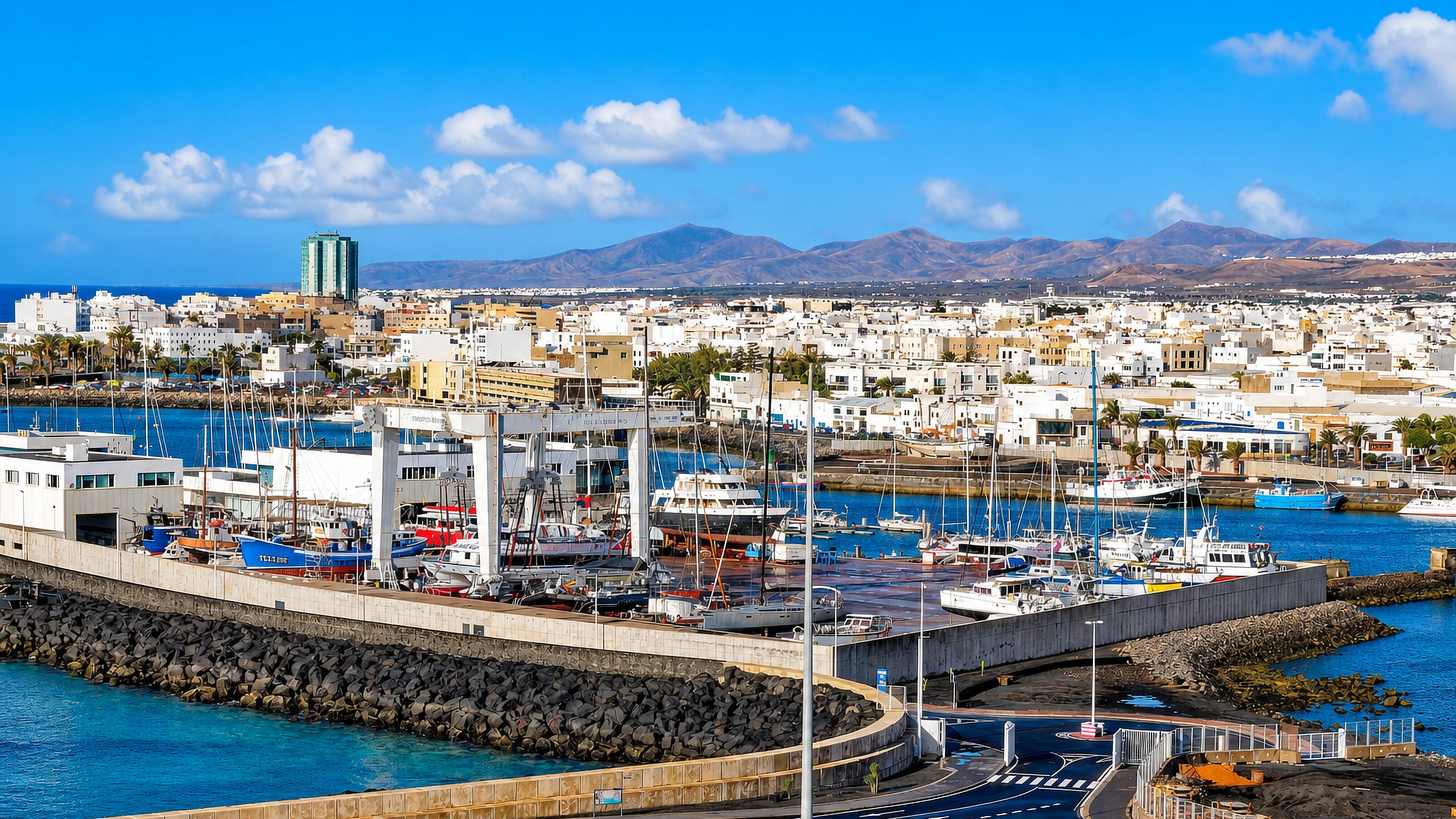 Marina and white low-rise town of Arrecife, Lanzarote, with volcanic hills on the horizon.