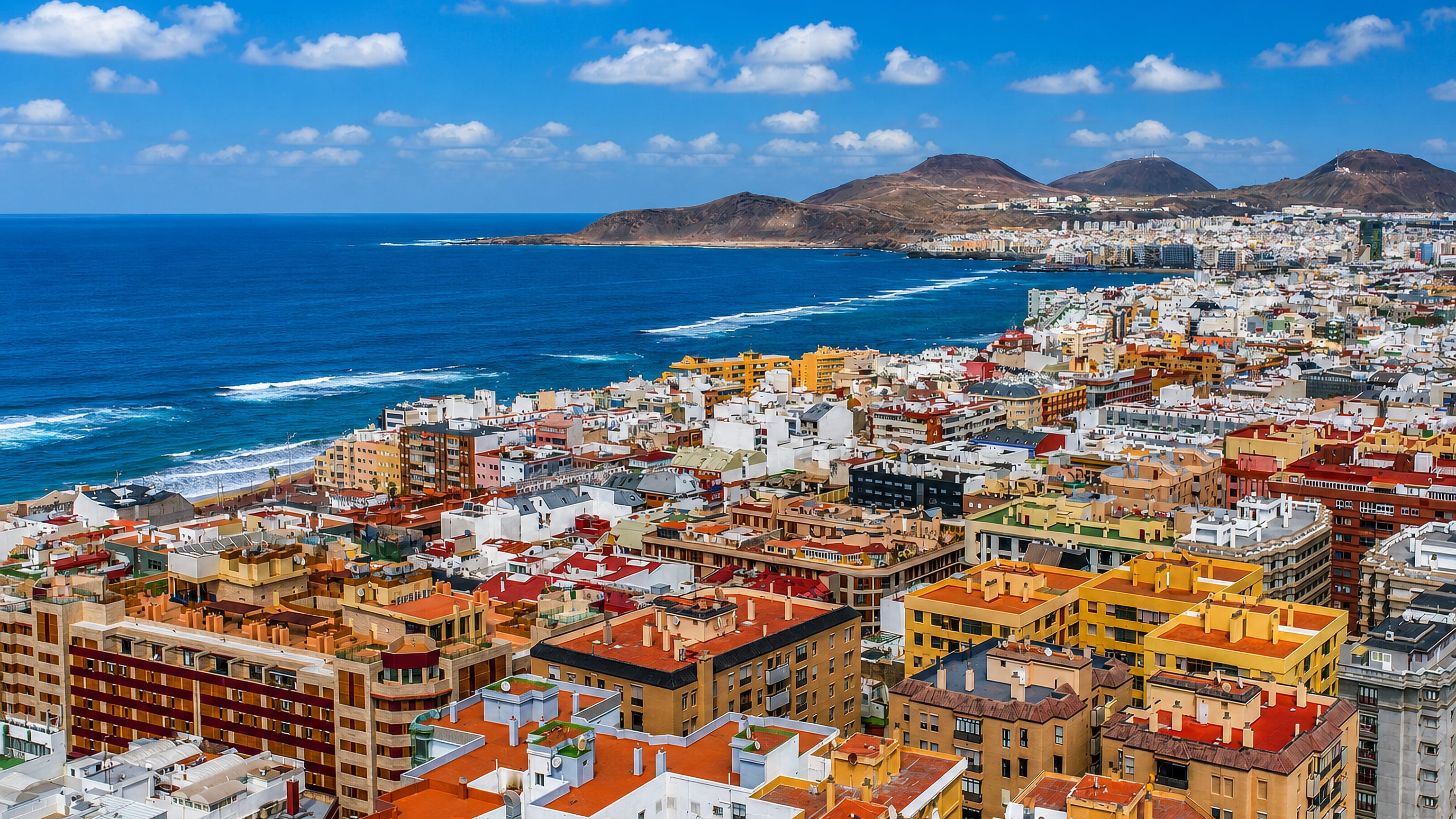 Las Palmas de Gran Canaria's colourful rooftops above Las Canteras beach, with the La Isleta headland beyond