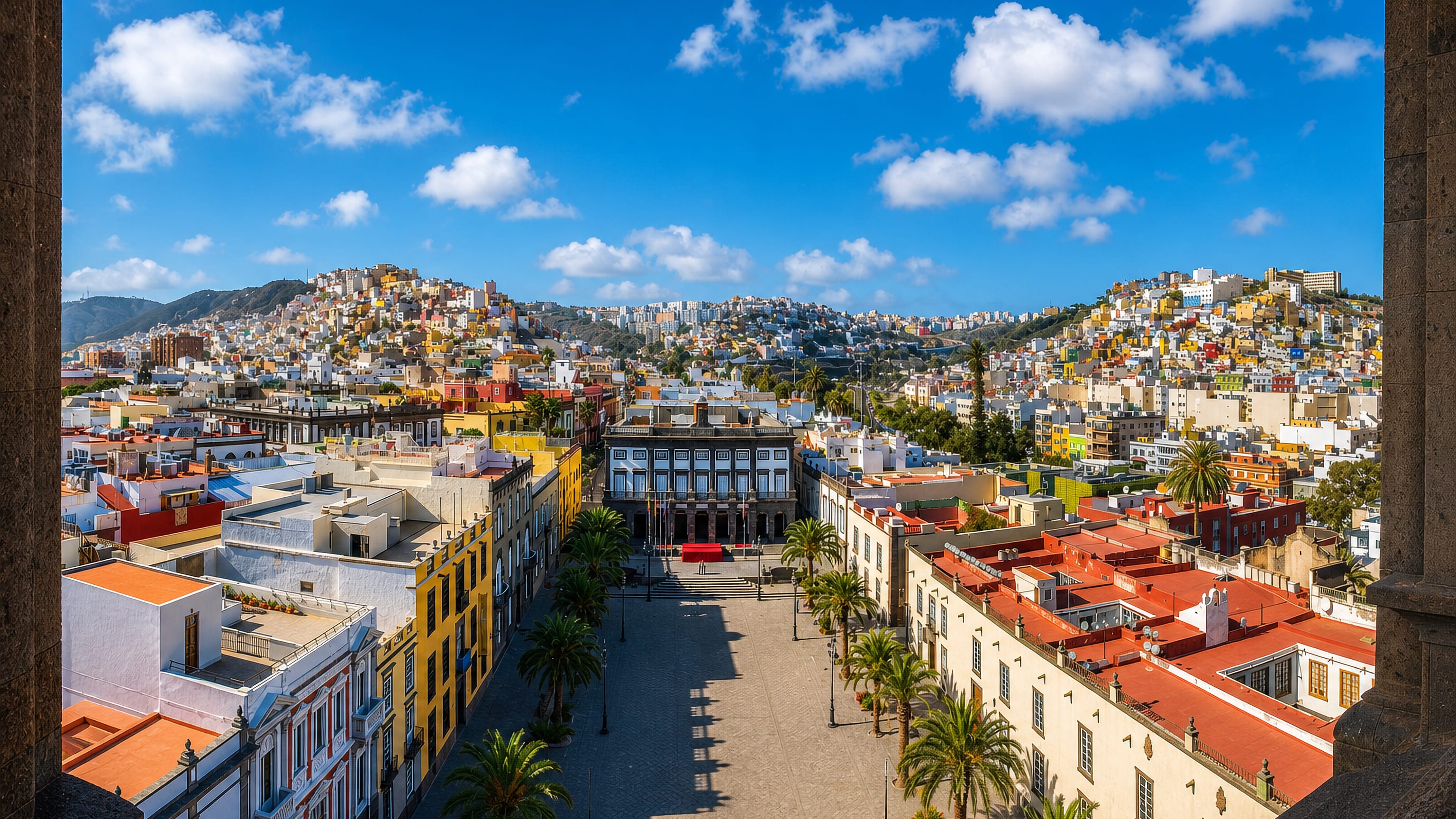 Plaza de Santa Ana and the town hall in Vegueta, Las Palmas de Gran Canaria, with palms and hillside houses.