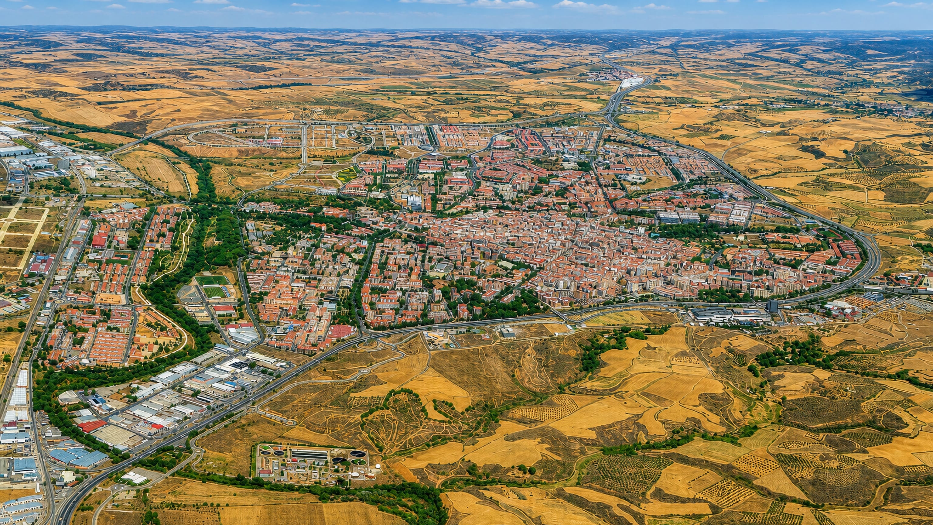 Guadalajara, Spain, seen from the air: a compact red-roofed city ringed by motorways amid dry Castilian farmland.
