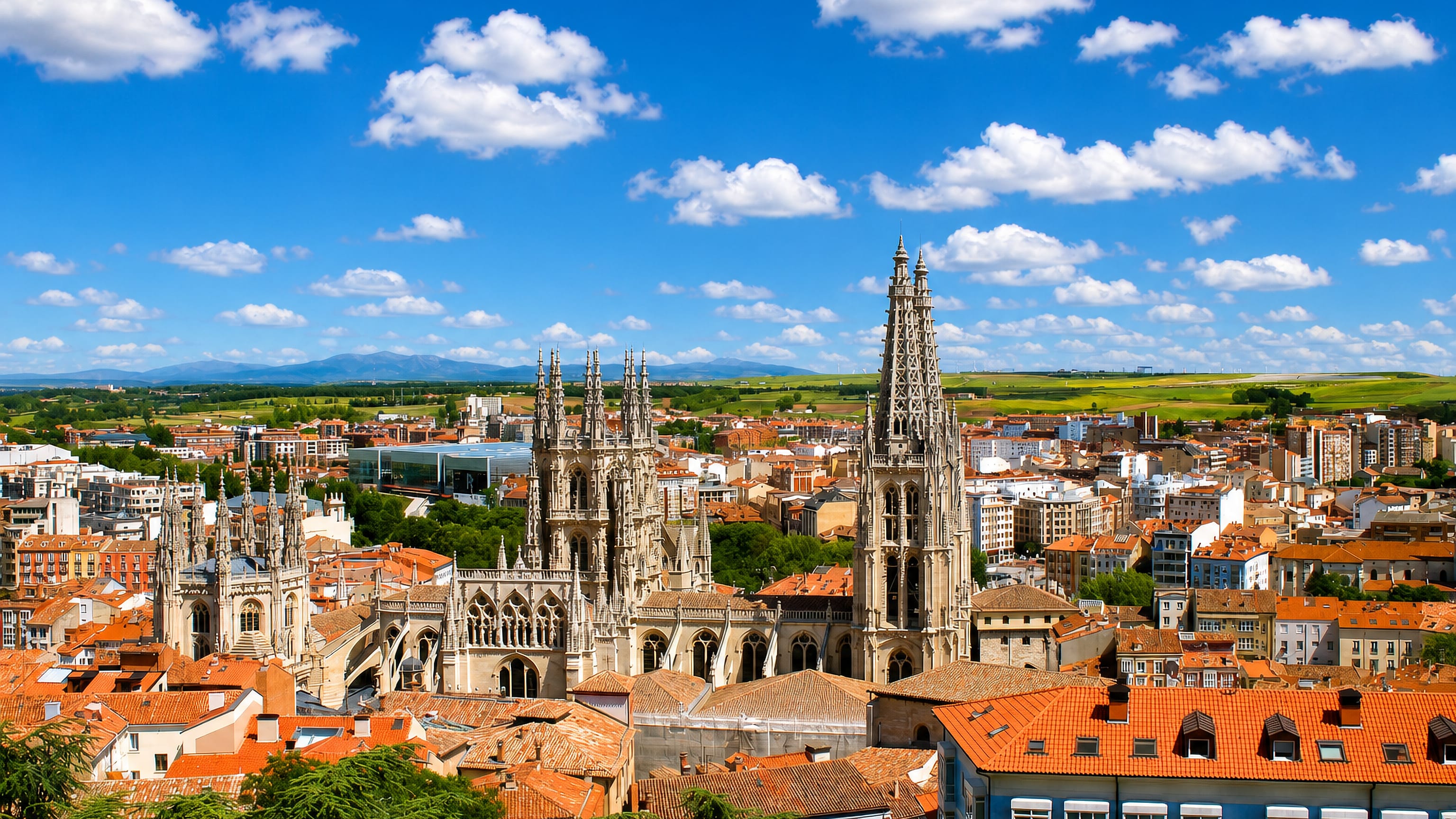 Burgos Cathedral's openwork Gothic spires rising above terracotta rooftops with the Castilian plain beyond