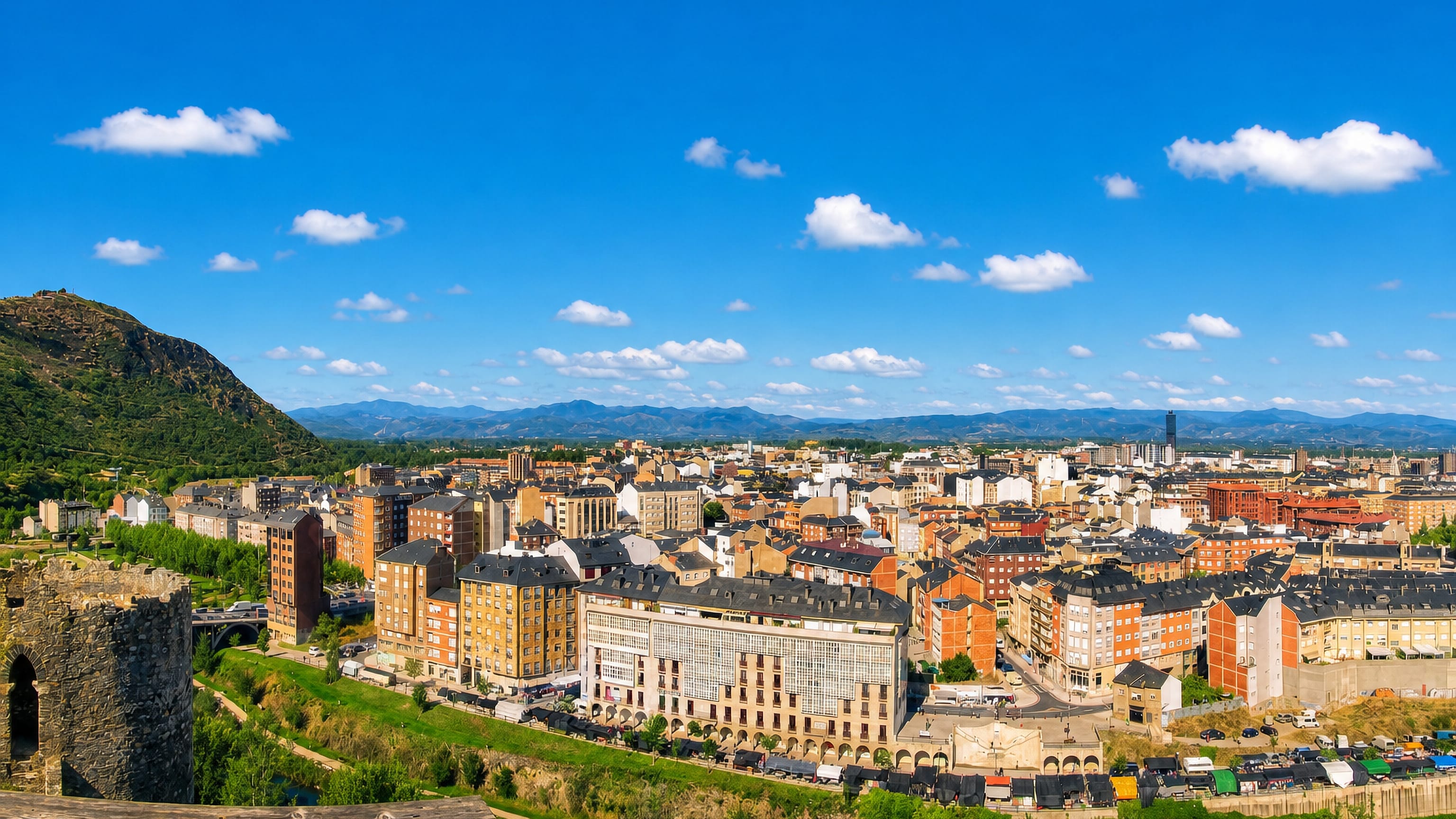 Ponferrada rooftops and the Sil valley seen from the Templar castle walls, with El Bierzo hills behind.