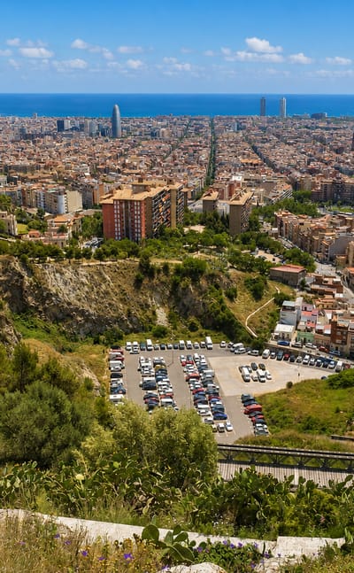 Panorama of Barcelona from the Can Baro hillside, with the Sagrada Familia, Torre Glories and the Mediterranean sea beyond the rooftops.