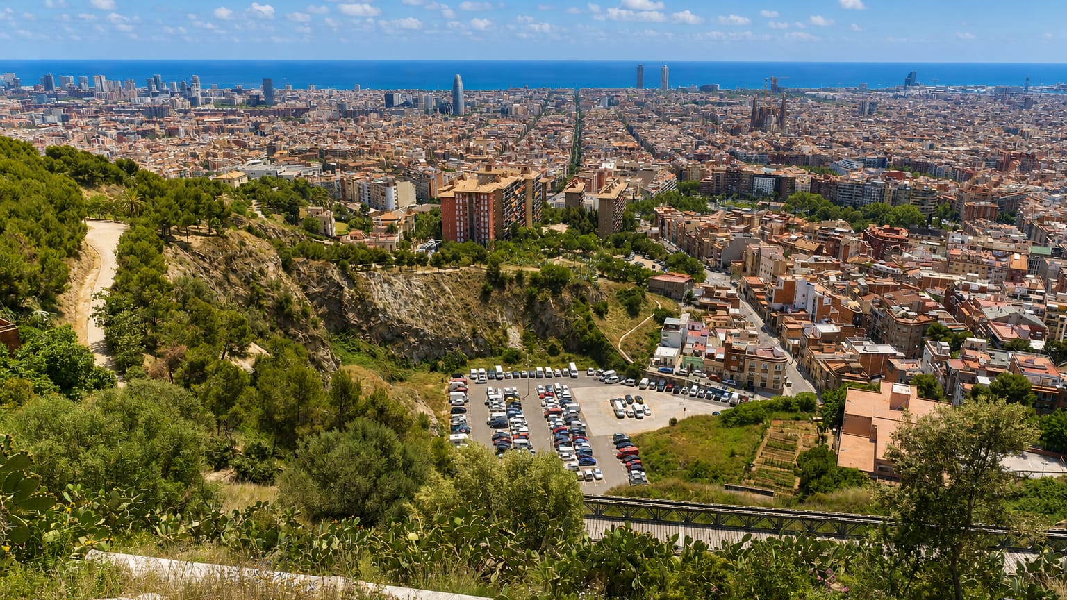 Panorama of Barcelona from the Can Baro hillside, with the Sagrada Familia, Torre Glories and the Mediterranean sea beyond the rooftops.