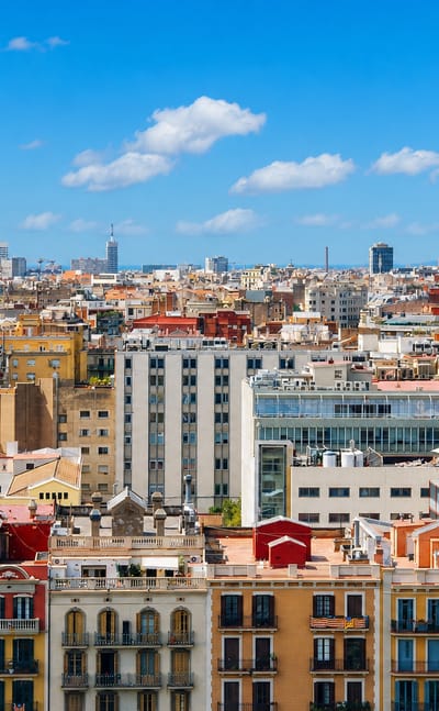 Wide rooftop panorama over Barcelona's Eixample showing ornate apartment facades and a sea of city rooftops