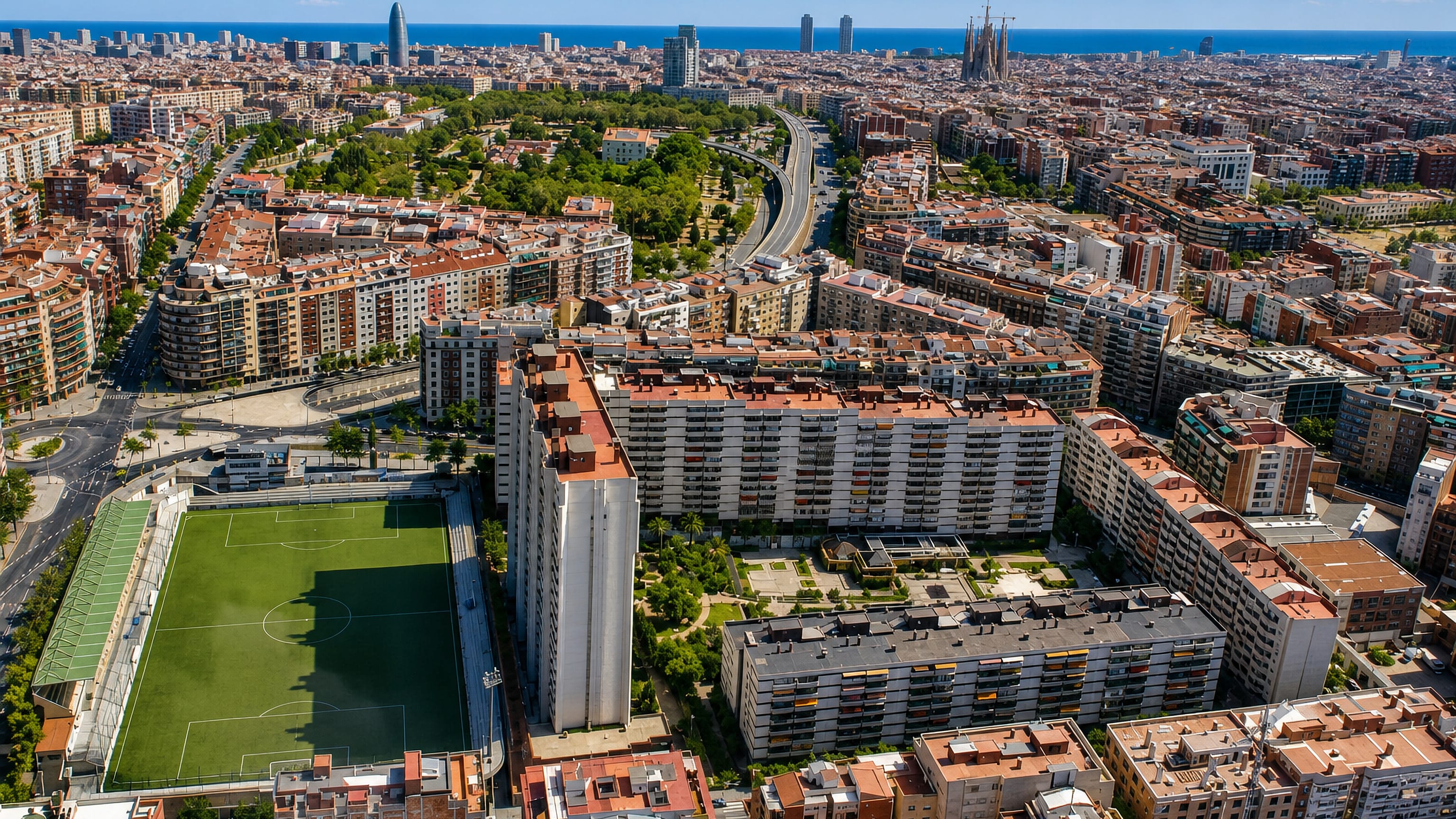 Aerial over el Camp d'en Grassot i Gràcia Nova in Barcelona toward the Sagrada Família and the sea