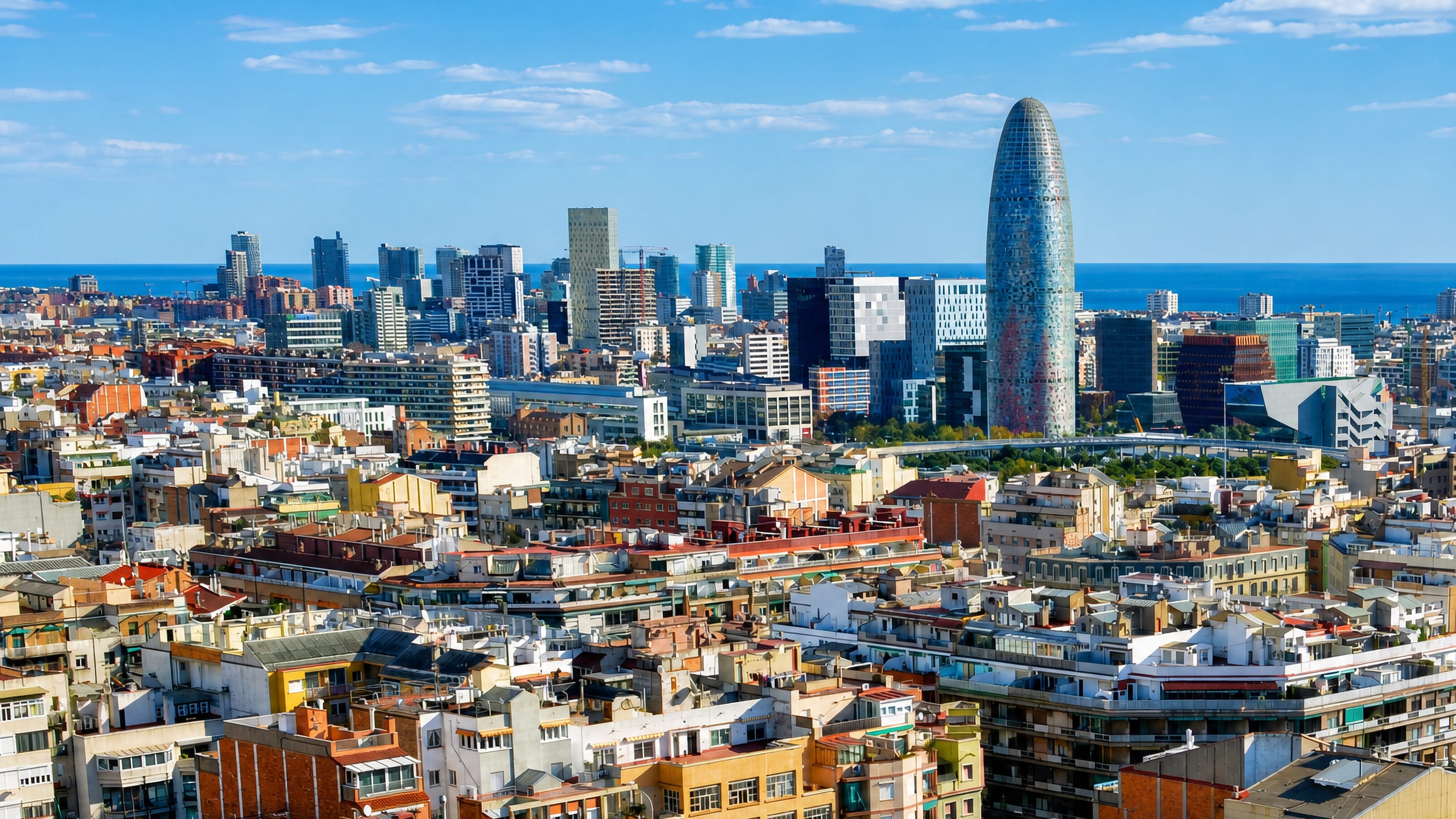 Barcelona rooftops at el Parc i la Llacuna del Poblenou with Torre Glòries and the Mediterranean beyond.