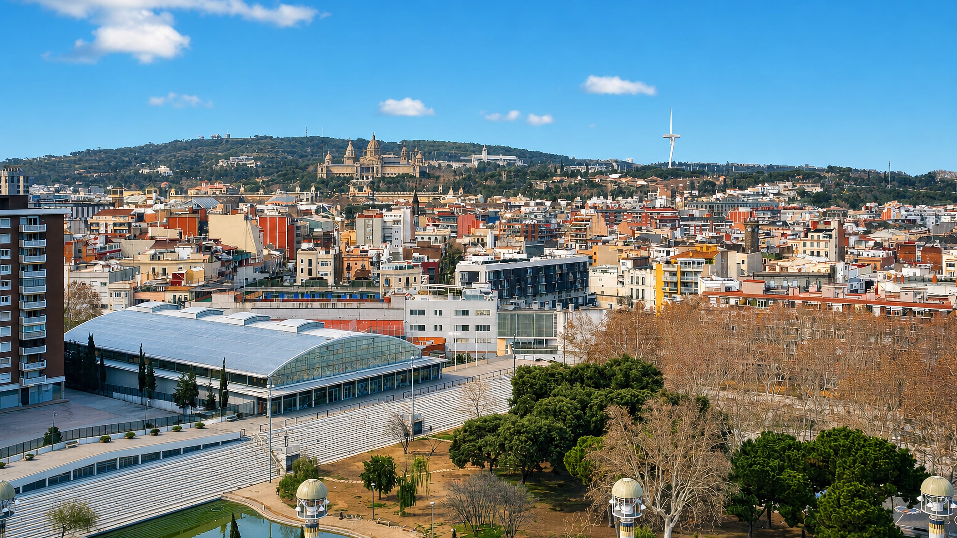 Hostafrancs rooftops in Barcelona below Montjuic, with the Palau Nacional and Calatrava tower on the ridge.