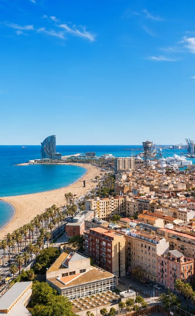 Aerial view of Barcelona's La Barceloneta beach, palm-lined promenade, neighbourhood grid and the sail-shaped W Hotel