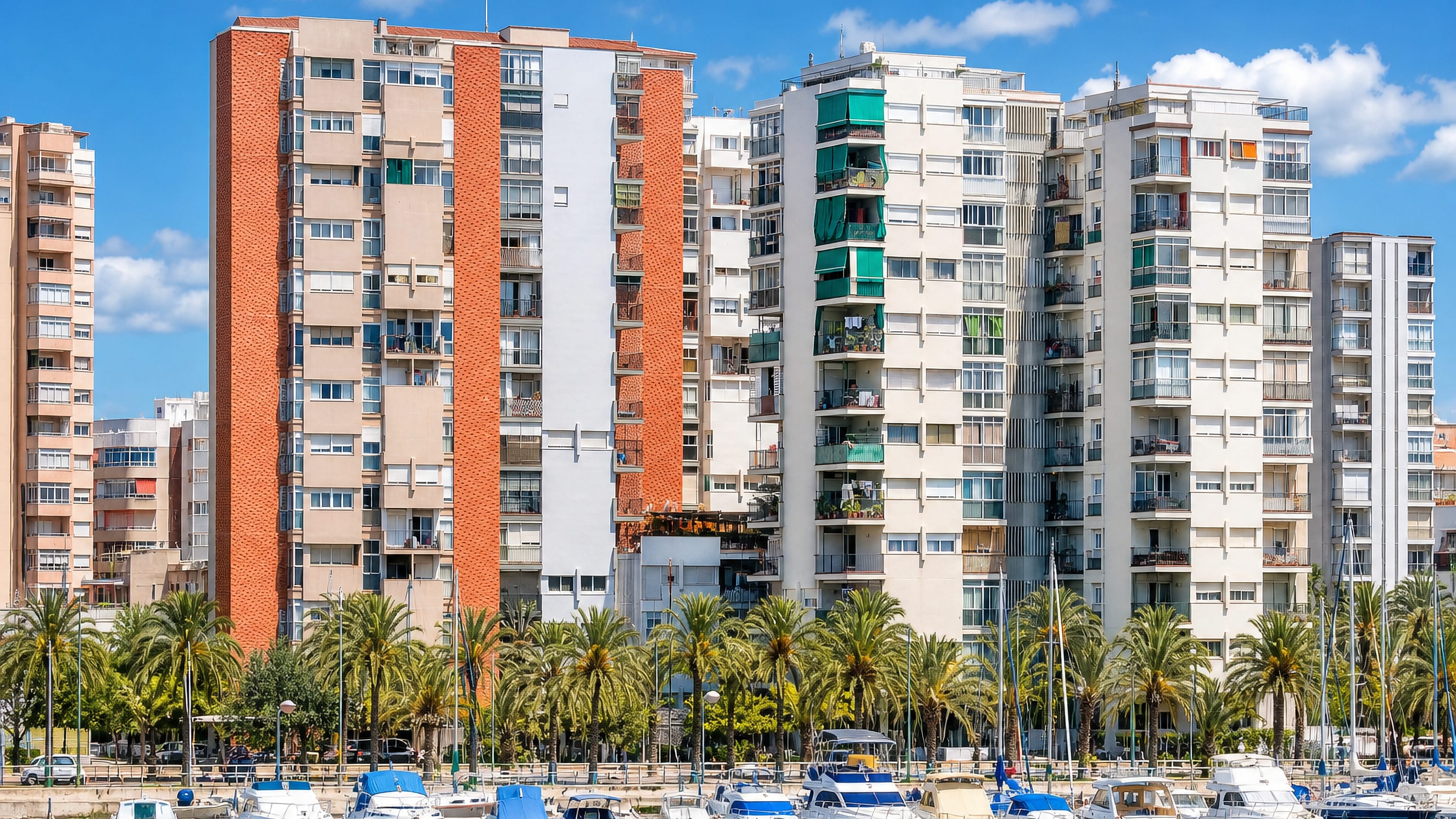 Yachts moored below palm-lined apartment towers in la Marina de Port, Barcelona.