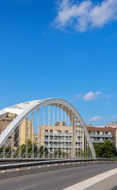 The white arched Bac de Roda bridge over apartment blocks in Sant MartI de Provencals, Barcelona, under a clear blue sky