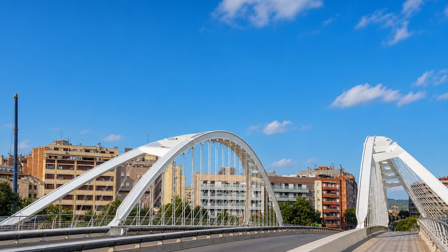 The white arched Bac de Roda bridge over apartment blocks in Sant MartI de Provencals, Barcelona, under a clear blue sky