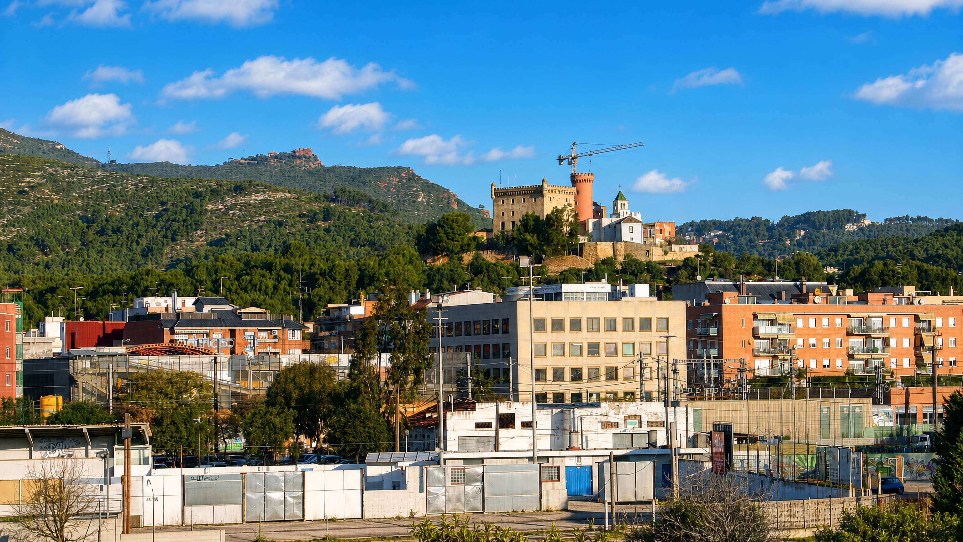 Castelldefels' hilltop castle and church above pine-covered hills, with the town's apartment blocks below