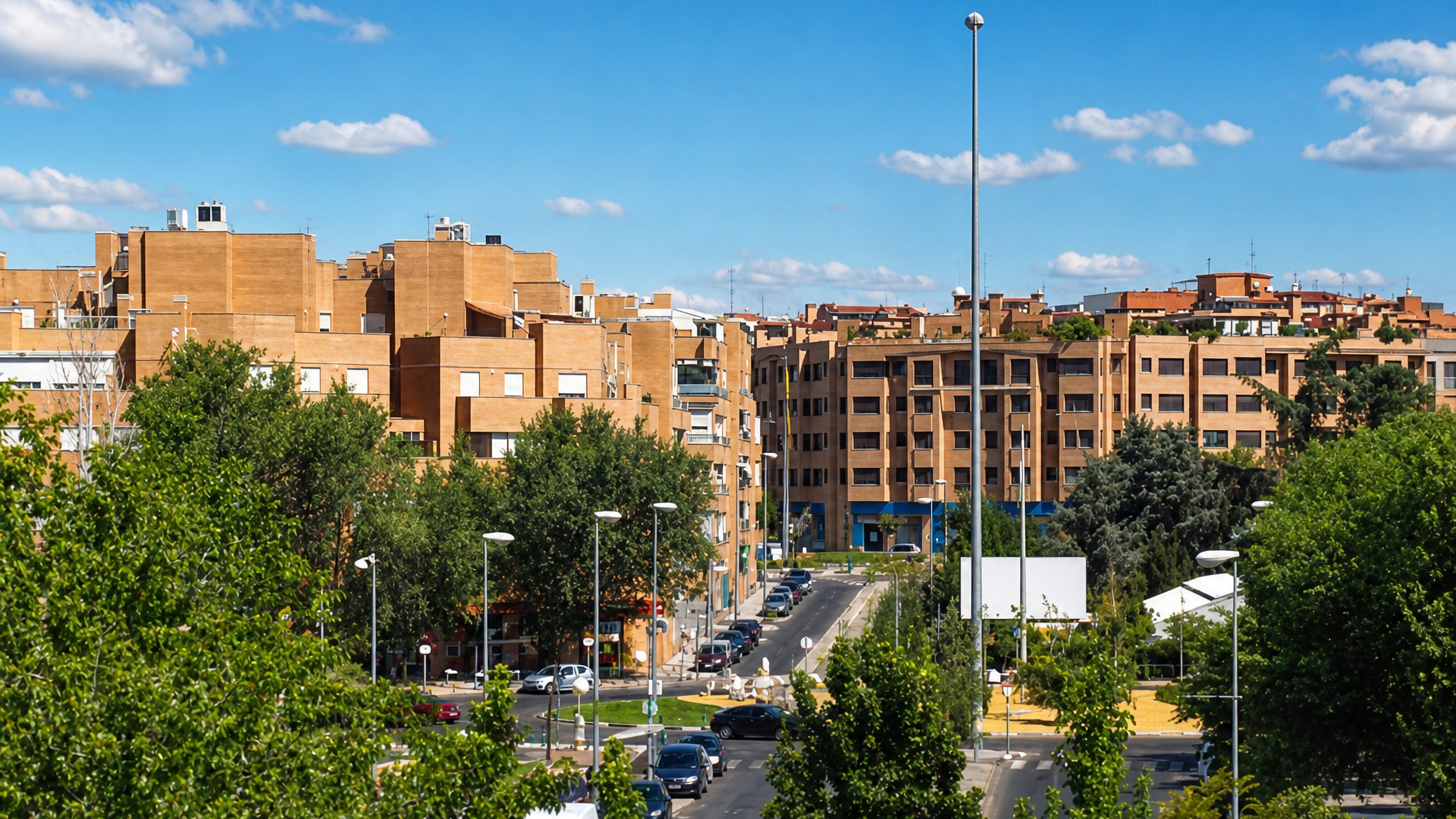 Brick apartment blocks and a tree-lined avenue under a clear blue sky in Alcobendas, north of Madrid
