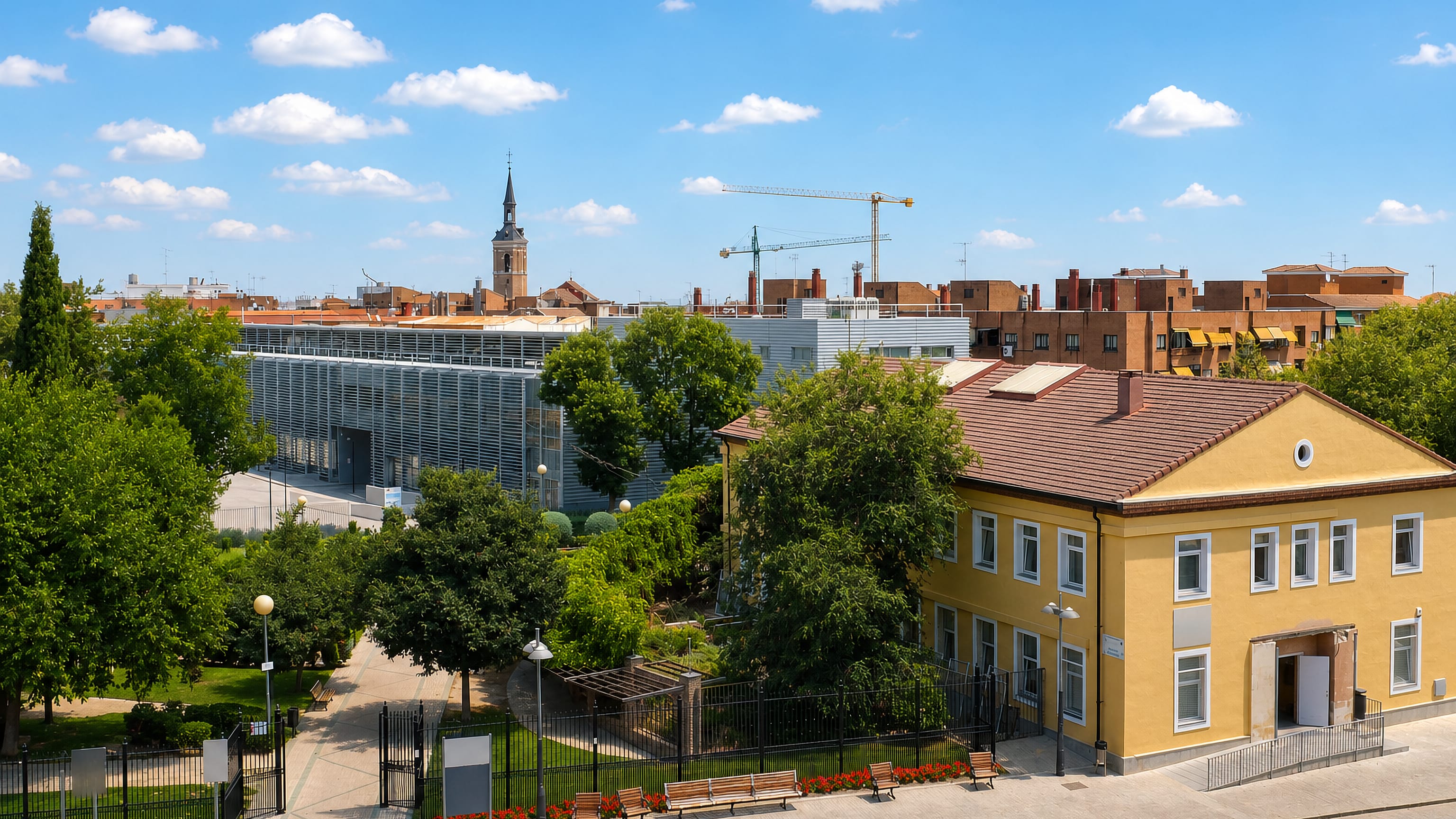 Parkland, brick housing and a church spire in Leganes, Madrid, Spain, seen over the treetops.