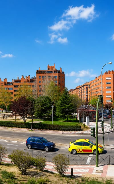 Red-brick apartment blocks and a tree-lined avenue in the Arcos district of Torrejón de Ardoz.