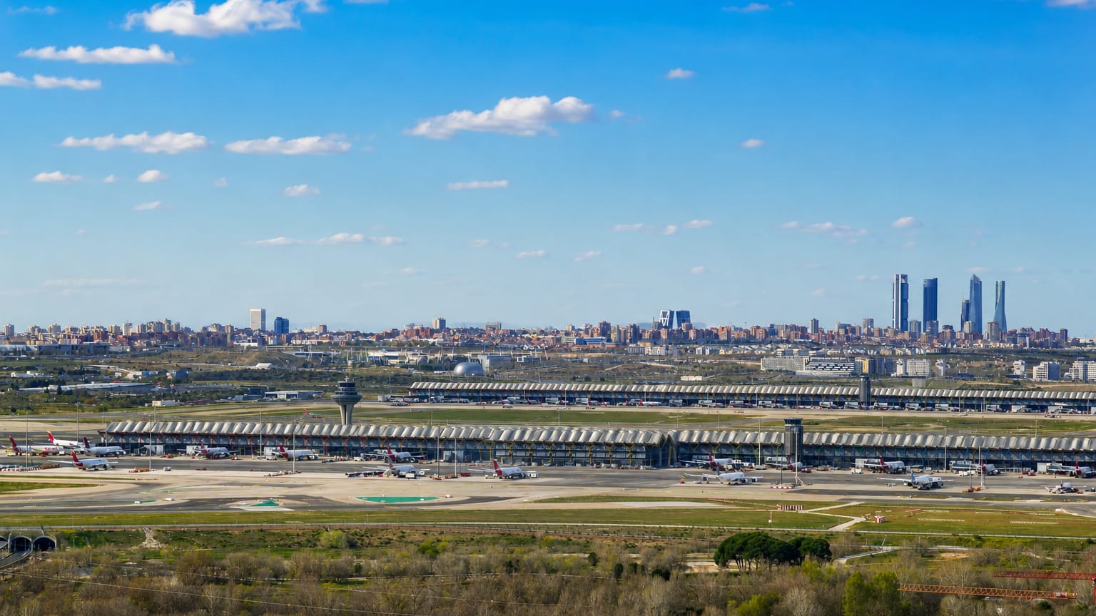 Madrid-Barajas Airport Terminal 4's wavy roof and control tower with the Cuatro Torres skyline behind, in the Barajas district