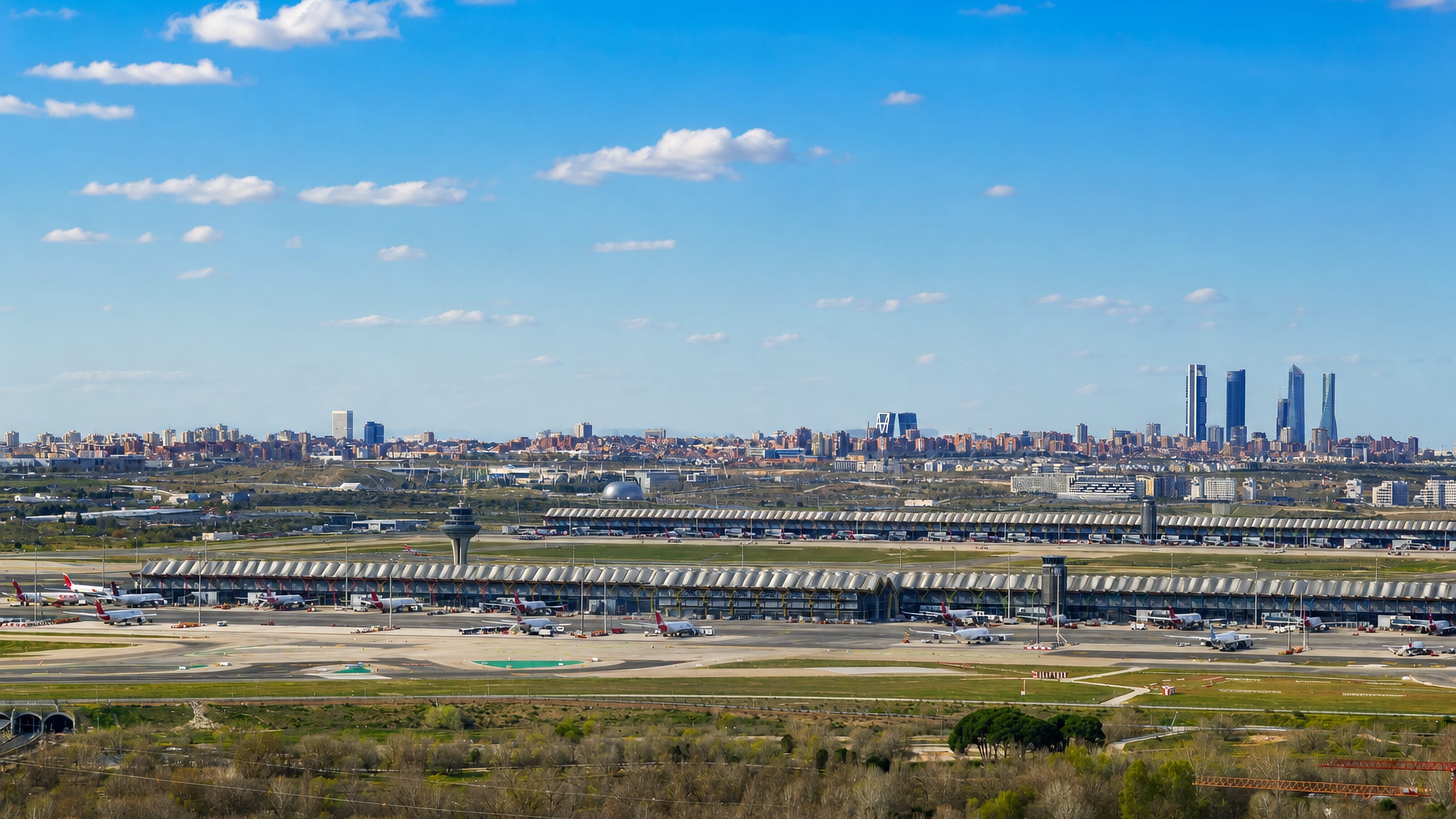 Madrid-Barajas Airport Terminal 4's wavy roof and control tower with the Cuatro Torres skyline behind, in the Barajas district