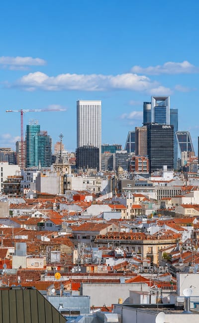 Wide daytime skyline of Madrid's Bellas Vistas district with terracotta rooftops rising toward the Cuatro Torres and Torre Picasso.