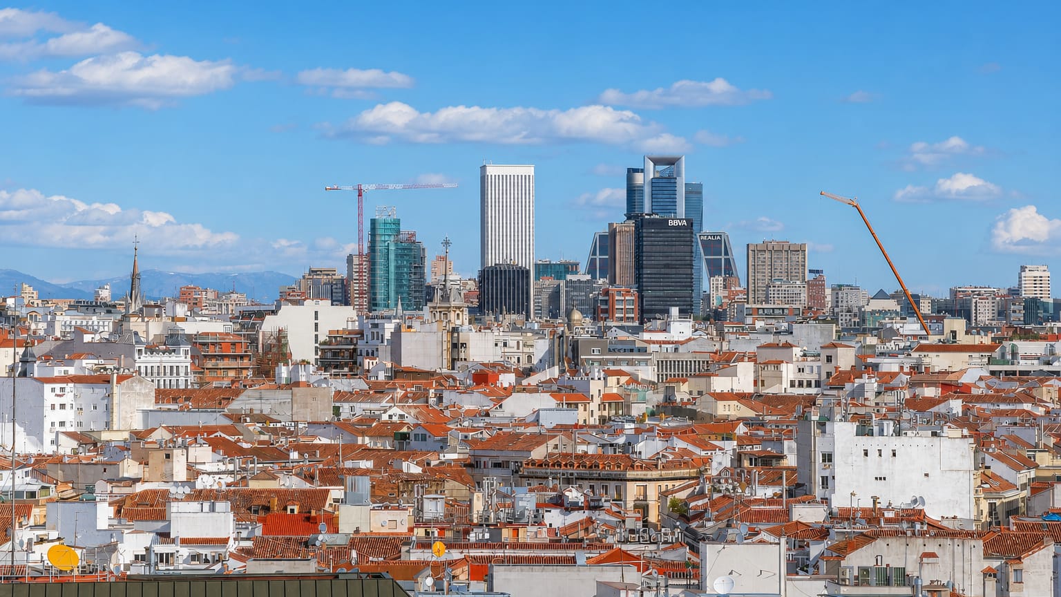 Wide daytime skyline of Madrid's Bellas Vistas district with terracotta rooftops rising toward the Cuatro Torres and Torre Picasso.