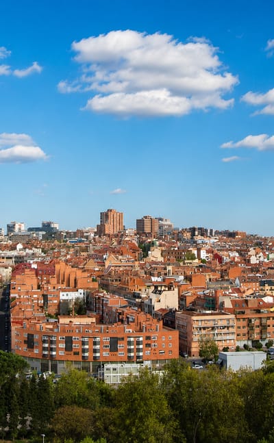 Wide daytime Madrid rooftop skyline with the Cuatro Torres and KIO towers on the horizon