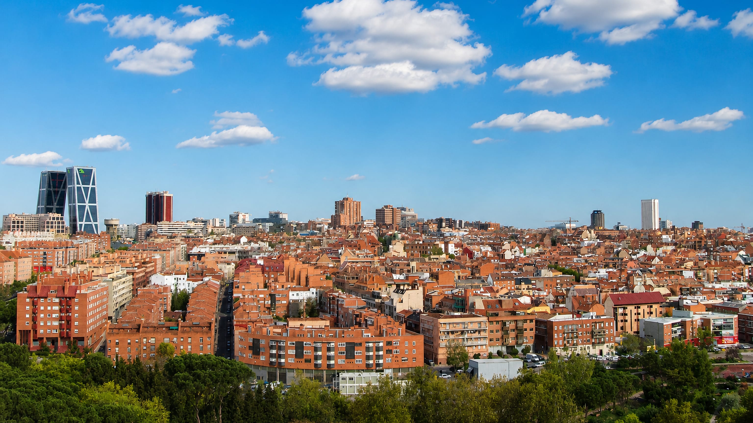 Wide daytime Madrid rooftop skyline with the Cuatro Torres and KIO towers on the horizon