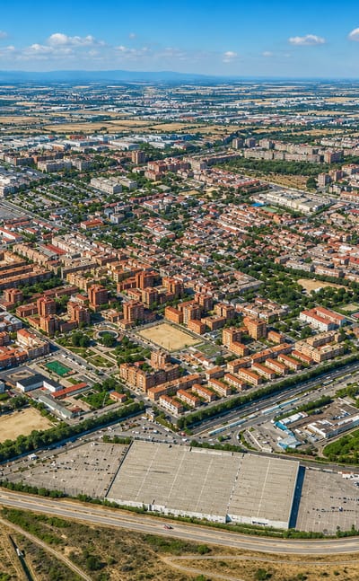 Aerial view of low-rise housing blocks and retail sheds in eastern Madrid's Canillejas district with the Sierra on the horizon