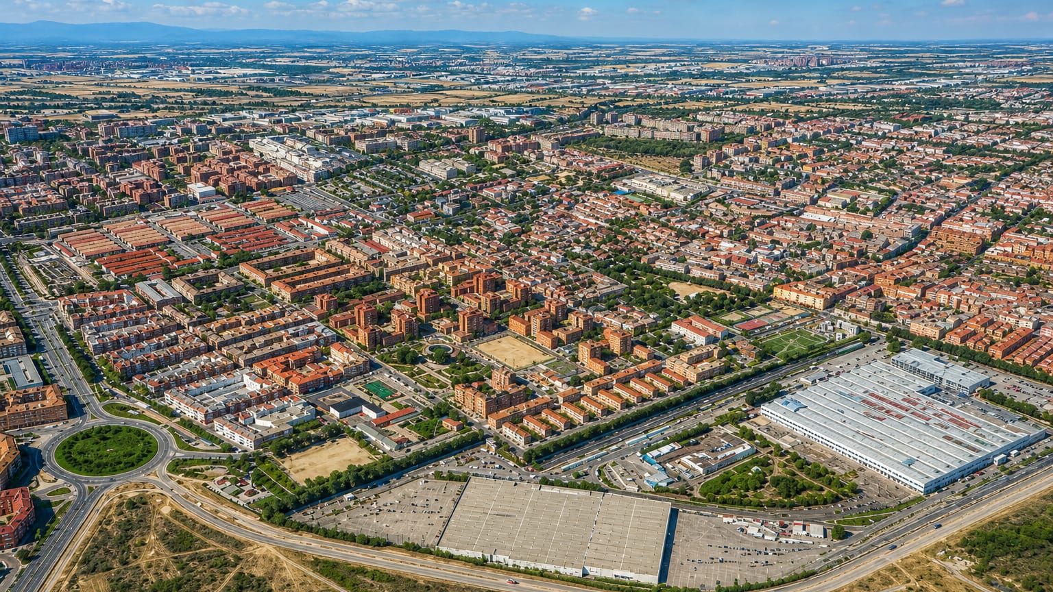 Aerial view of low-rise housing blocks and retail sheds in eastern Madrid's Canillejas district with the Sierra on the horizon