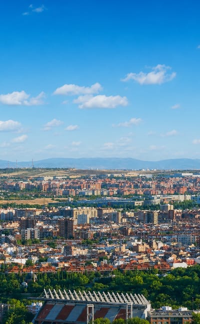 Aerial panorama of the low-rise residential district of Carabanchel spreading toward Madrid's sierra on the horizon.