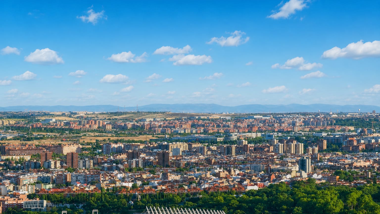 Aerial panorama of the low-rise residential district of Carabanchel spreading toward Madrid's sierra on the horizon.