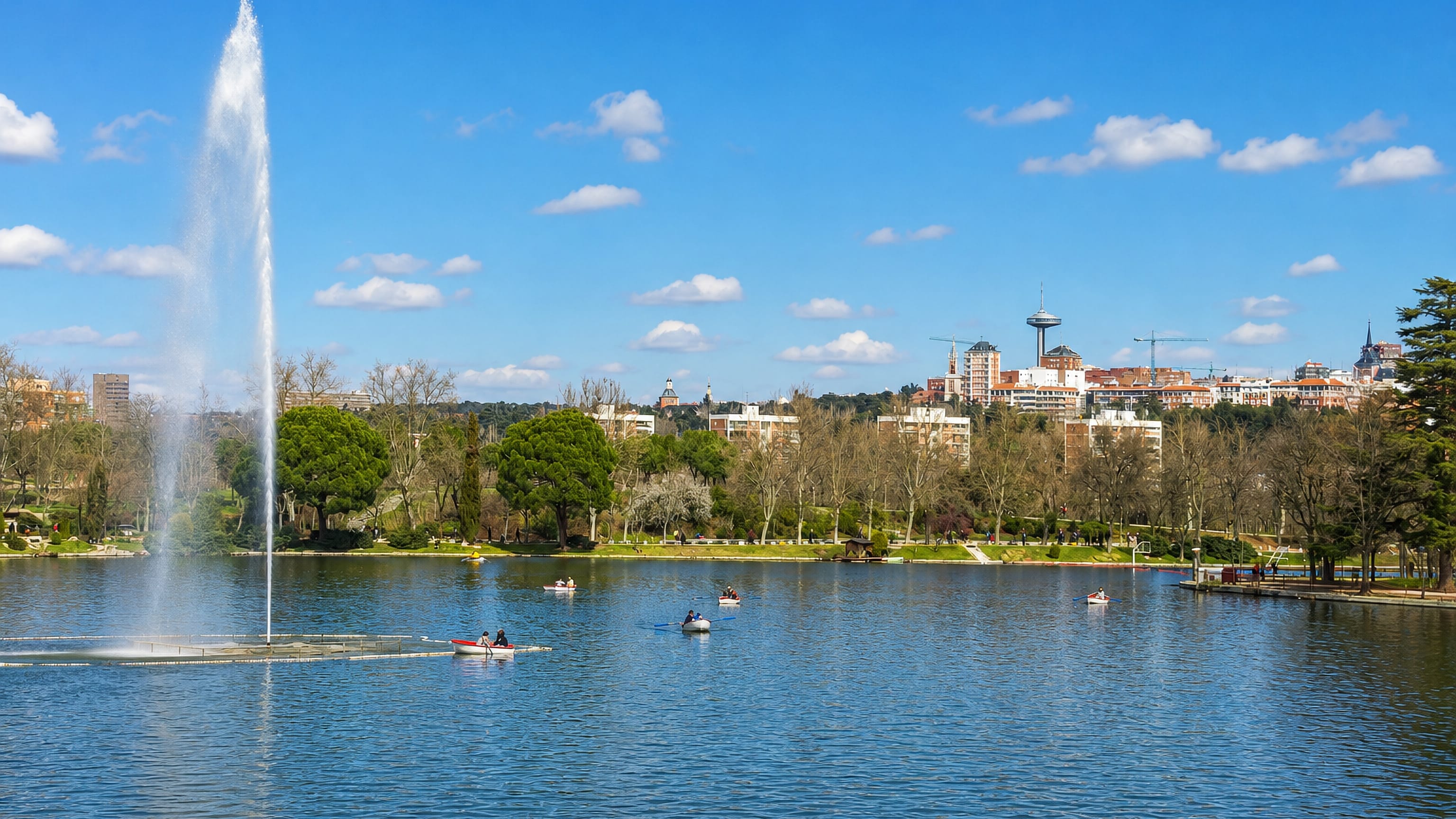 Fountain and rowing boats on the lake in Casa de Campo, Madrid, with the Faro de Moncloa on the skyline.