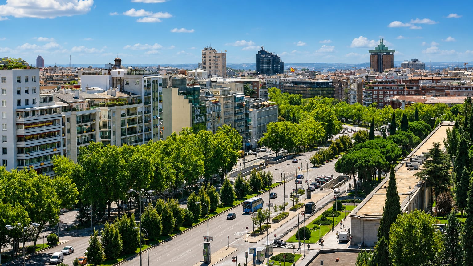 Leafy tree-lined boulevard and mid-rise residential blocks with the Madrid skyline in the El Viso district.
