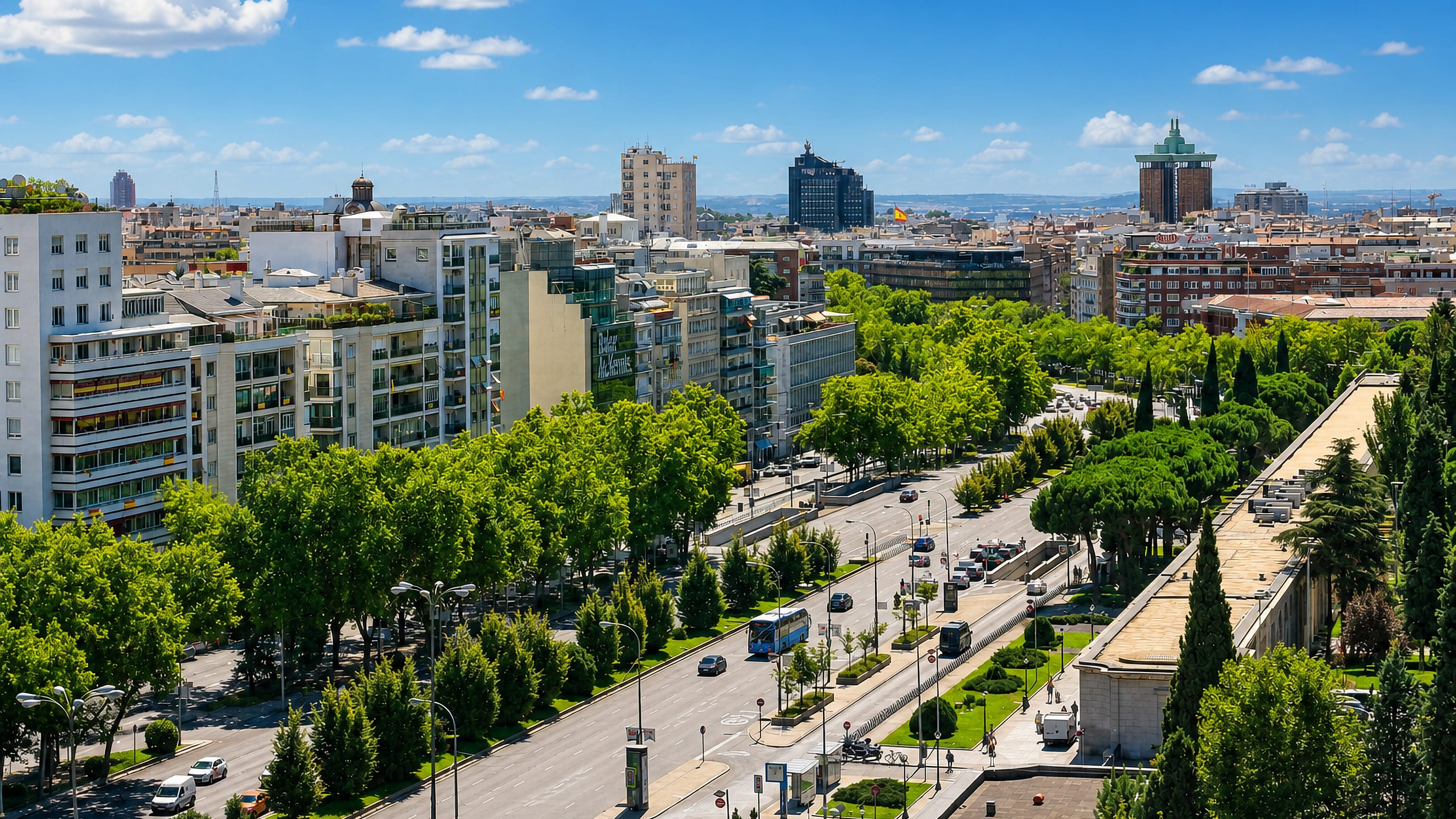 Leafy tree-lined boulevard and mid-rise residential blocks with the Madrid skyline in the El Viso district.
