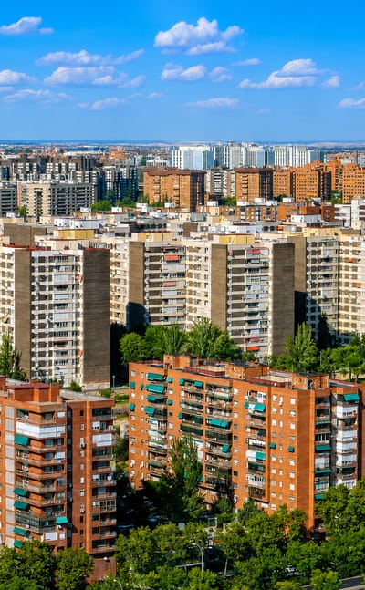 Aerial view of Fuencarral-El Pardo's dense residential tower blocks and parkland under a blue Madrid sky