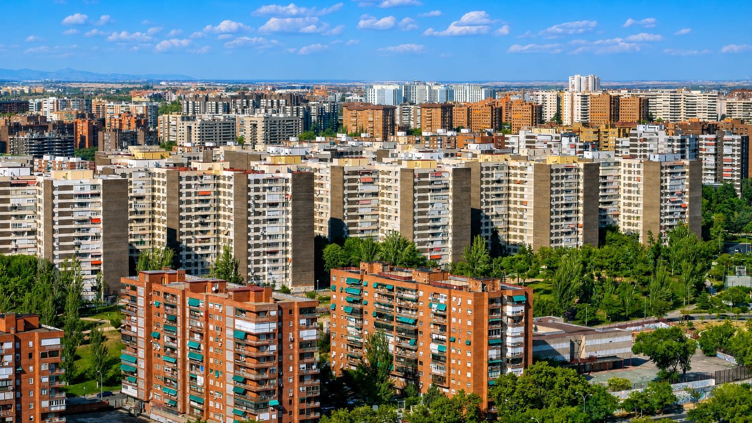 Aerial view of Fuencarral-El Pardo's dense residential tower blocks and parkland under a blue Madrid sky