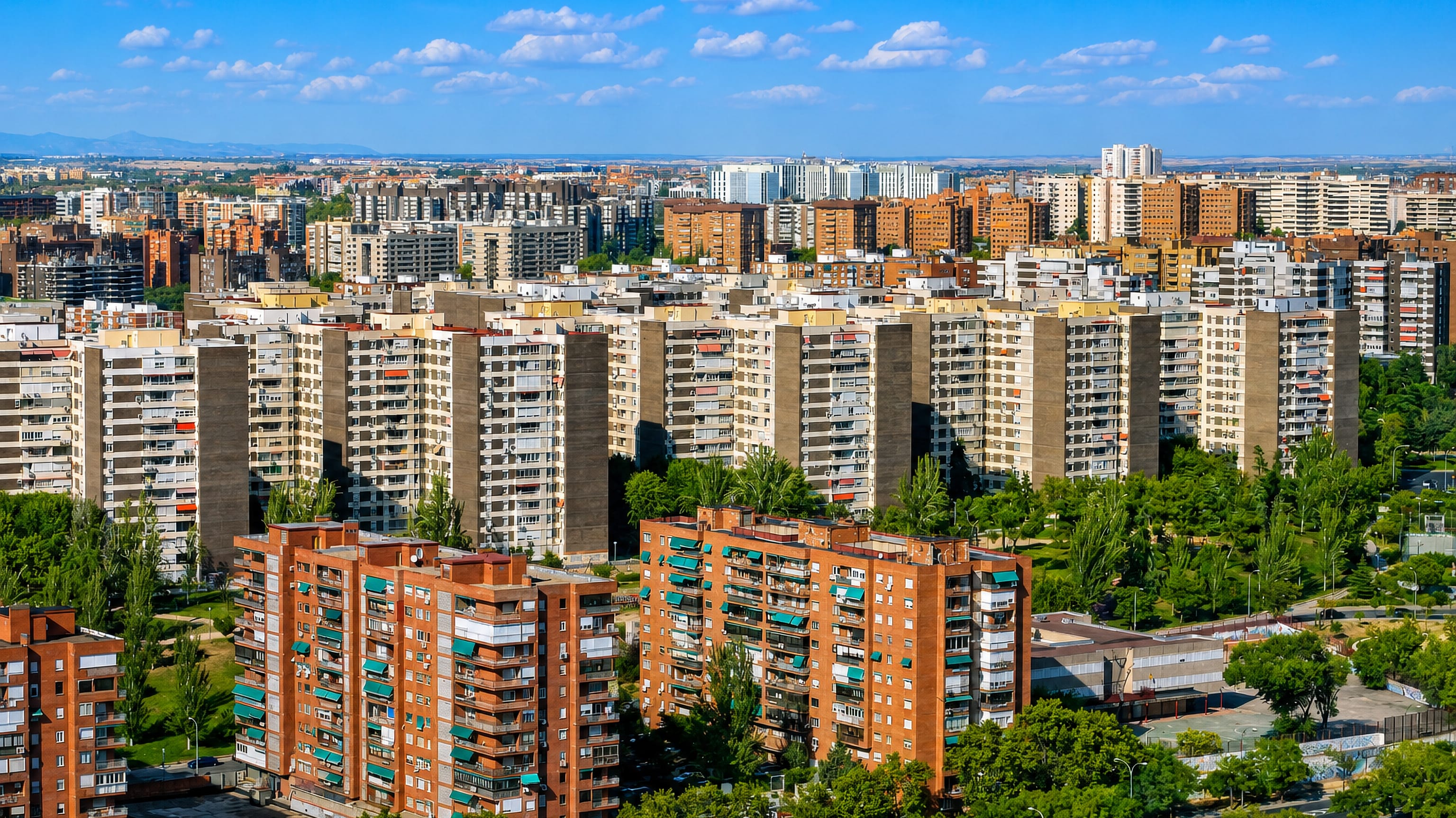 Aerial view of Fuencarral-El Pardo's dense residential tower blocks and parkland under a blue Madrid sky