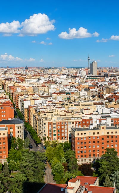 Aerial view of dense mid-rise residential blocks and tree-lined streets across the Gaztambide neighborhood of central Madrid.