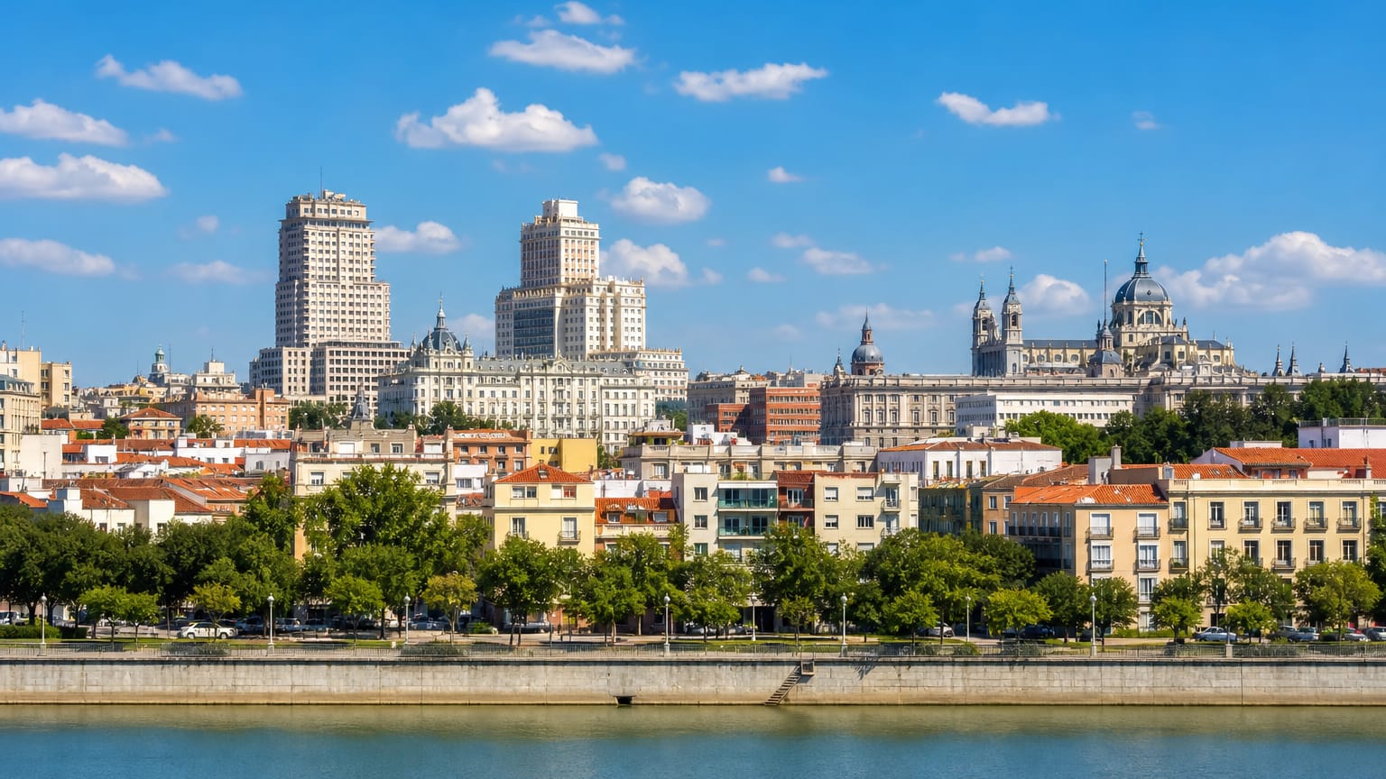 Madrid skyline across the Manzanares river with the Torre de Madrid, Edificio Espana and the domes of the Almudena Cathedral.