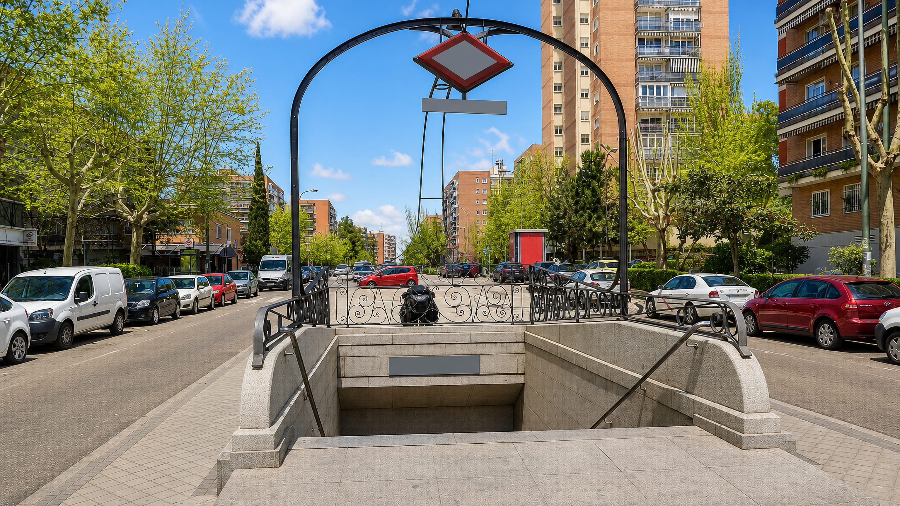 Madrid Metro entrance with arched ironwork on a tree-lined street of brick apartment blocks in Hortaleza.