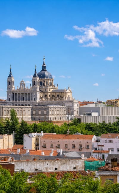 The Royal Palace of Madrid and the domed Almudena Cathedral rising over rooftops in the Palacio neighborhood.