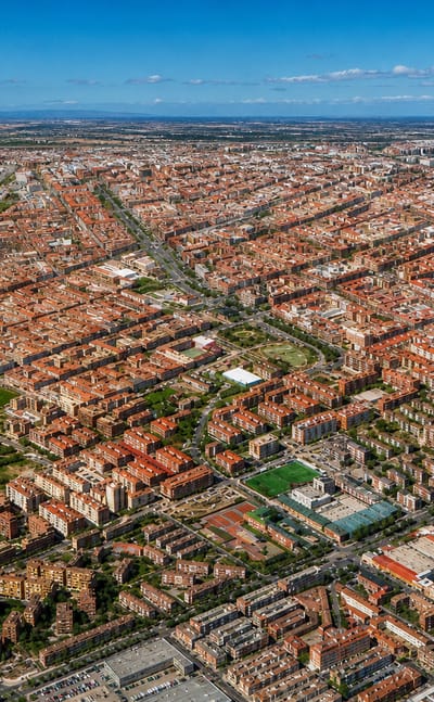 High aerial view over Pueblo Nuevo's gridded red-roofed streets stretching across eastern Madrid