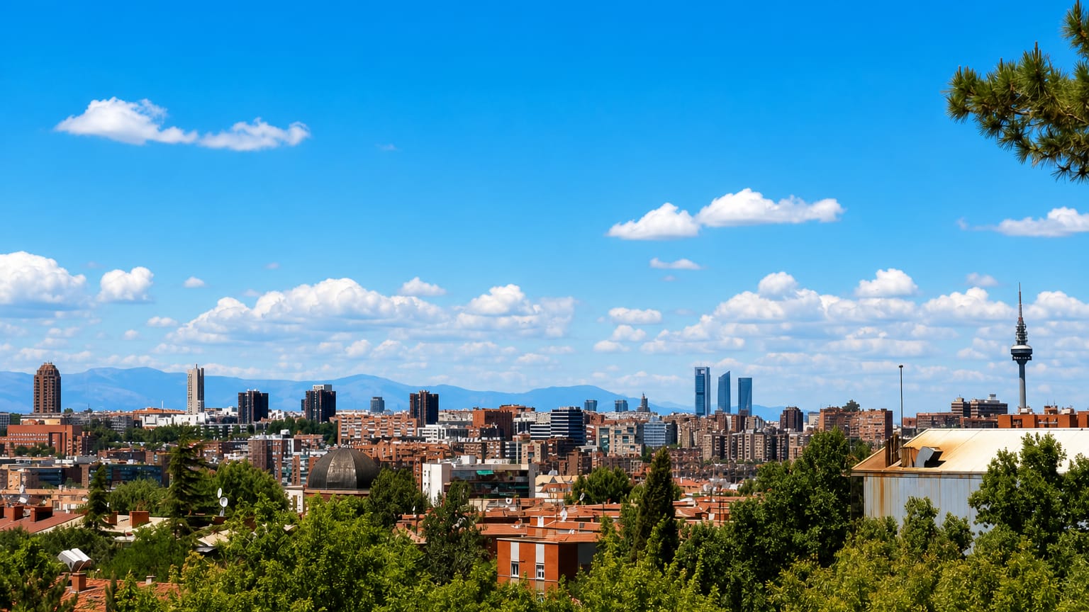 Madrid skyline from a green hill showing the Cuatro Torres and Torrespana tower above red-tiled rooftops near Puente de Vallecas