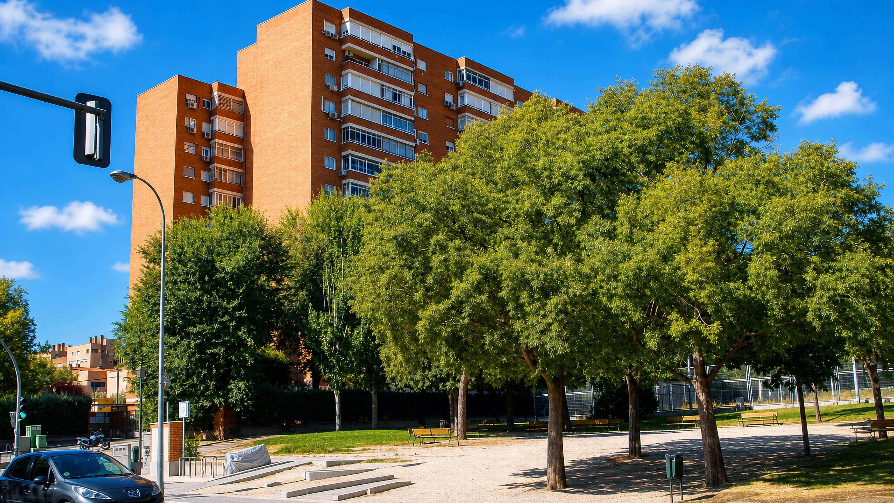 Brick apartment towers rising above a tree-shaded plaza in the San Fermín district of Madrid.