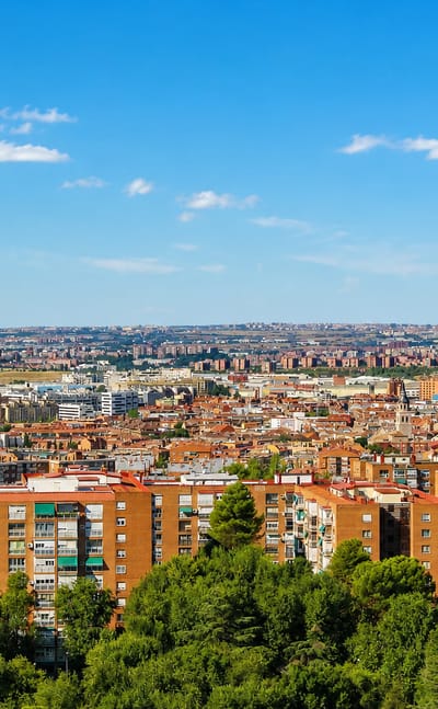 Aerial view of red-brick apartment blocks amid trees with Madrid's metropolitan sprawl stretching to the horizon in Santa Eugenia.